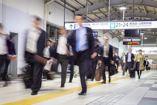 Corporate business people commuting to work by Tokyo public transport. Unrecognizable people blured in motion while rushing to train platforms.