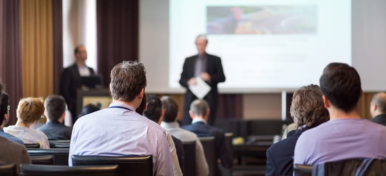 Speaker Giving a Talk at Business Meeting. Audience in the conference hall. Business and Entrepreneurship. Panoramic composition suitable for banners.