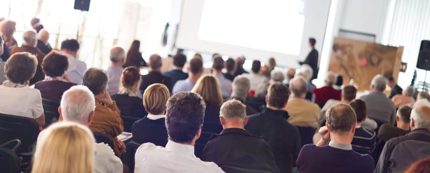 Speaker Giving a Talk at Business Meeting. Audience in the conference hall. Business and Entrepreneurship. Panoramic composition suitable for banners.