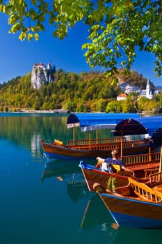 Traditional wooden boats on lake Bled in autumn, with the rocktop castle in the background. Slovenia