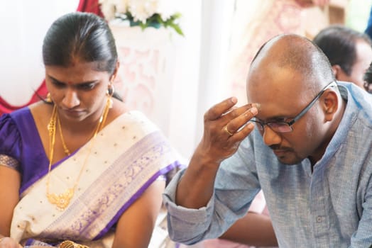 Hindu man putting tilak or marking on his forehead during Indian traditional religious rituals, the tradition of Hinduism.