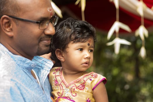 Candid shoot of Indian father and daughter in blessing ceremony. Traditional India family outdoor portrait.