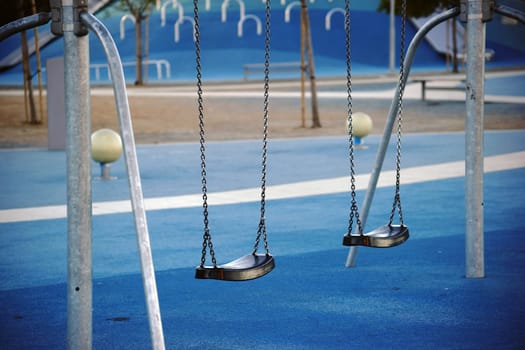 A modern playground in the city with laid rubber mats,swings and slides.