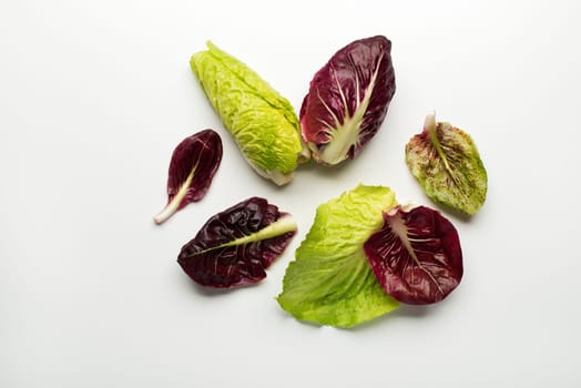 Fresh mixed salad leaves with radicchio on a white background.