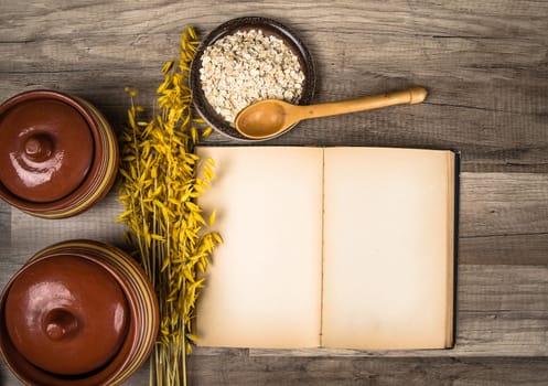 The top view on the opened cookbook and kitchen utensils