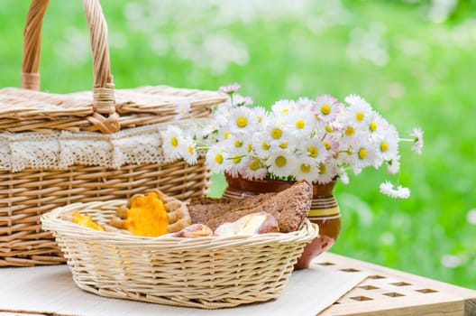 Buns in a wicker basket and a bouquet of flowers