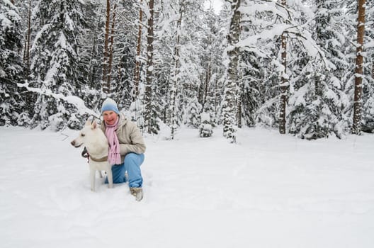 The woman with a dog on walk in a winter wood