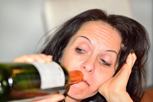 Young drunk woman with a bottle of red wine