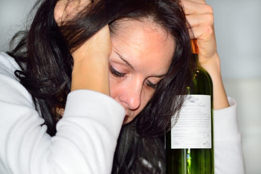 Young drunk woman with a bottle of red wine