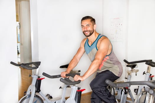 Young athletic man on training on the ergometer