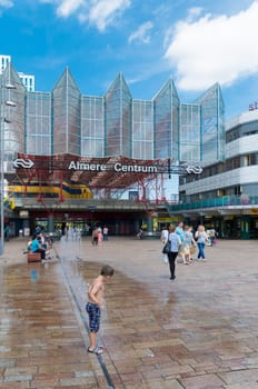 Central train station in Almere, Netherlands on a hot day. The station opened may 1987 and is designed by Peter Kilsdonk. Under the station lies a bus station