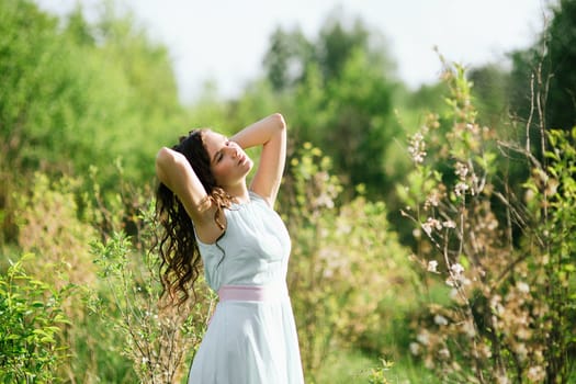 The girl with a beautiful hairdress poses against the wood in sun beams