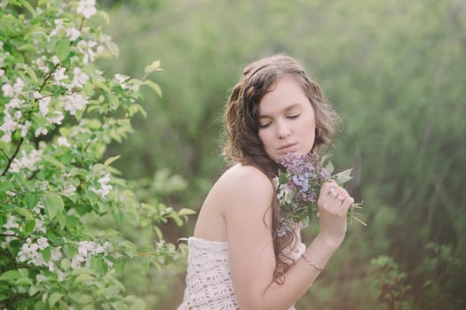 the girl with naked shoulders poses with a bouquet of wild flowers in cloudy weather