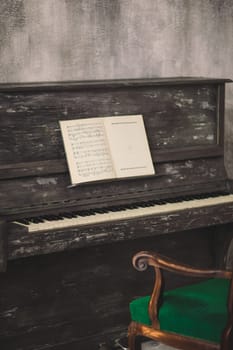 the old piano with notes costs in the old room with a green chair