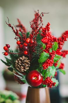 The bouquet from red berries with apple and the cone costs in a vase
