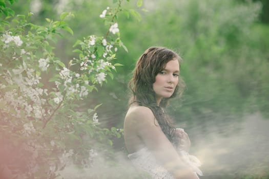 the girl with naked shoulders poses with a bouquet of wild flowers in cloudy weather
