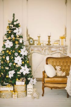 New Year's and Christmas interior in gold color with a chimney portal, a fir-tree and gifts