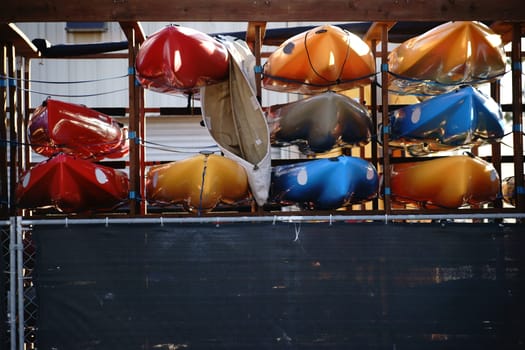 A number of canoes are stacked on a shelf of a boat rental.