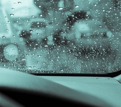 Blurry car seen through wet windscreen in rainy day. Green monochrome image