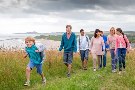 A family are walking on the sand dunes, they are all smiling and talking amounst themselves.