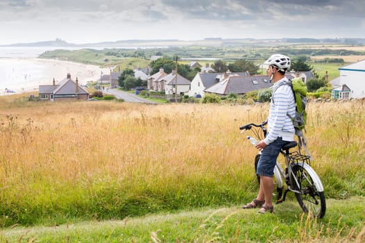A male is sitting on his bike and the beach, enjoying the view.