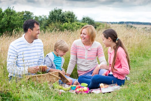 A family of four are sat on the sand dunes having a picnic