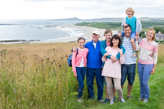 A family are standing on the sand dunes, they are all smiling and looking at the camera.