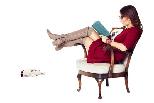Attractive woman reading a book while sitting comfortably in an old chair.