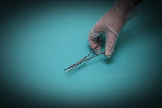 Hand holding a pair of clamp scissors on a blue background