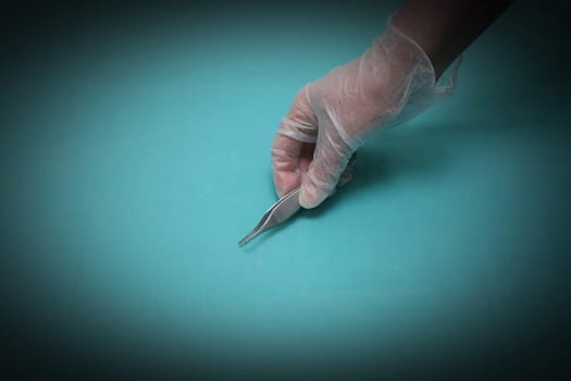 Hand holding tweezers on a blue background