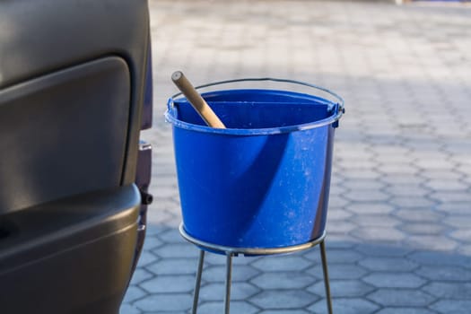 Blue bucket with water at a gas station to clean the windshield.