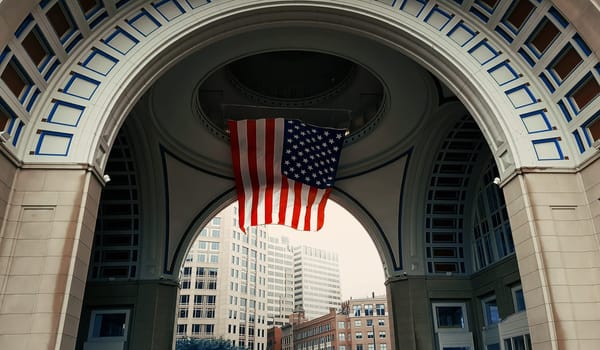 Looking through the arch at Rowes Wharf, in Boston, Massachusetts. USA flag hoisted