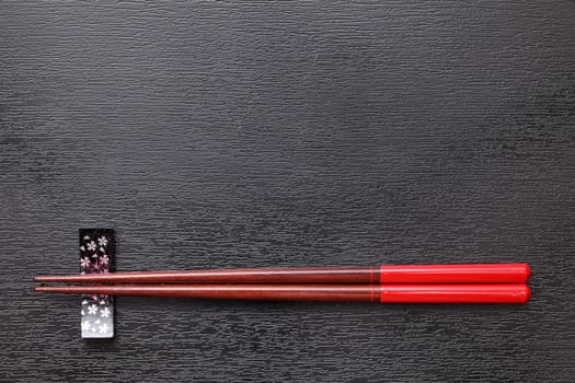 Chopsticks and chopsticks rest on black tray background