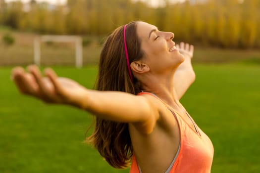 Beautiful woman in nature open her arms and smiling