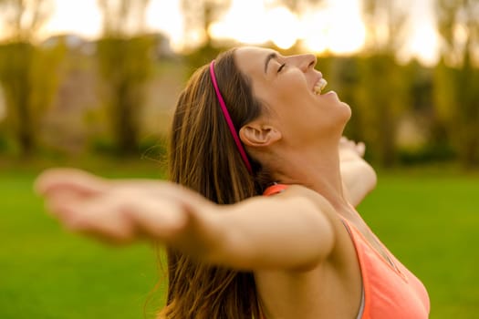 Beautiful woman in nature open her arms and smiling