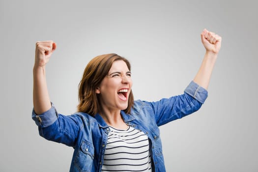 Studio portrait of a happy woman with arms raised