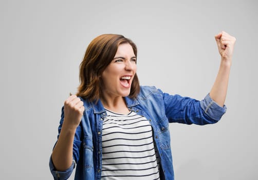 Studio portrait of a happy woman with arms raised