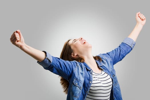 Studio portrait of a successful woman with arms raised