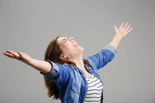 Studio portrait of a happy woman with arms raised