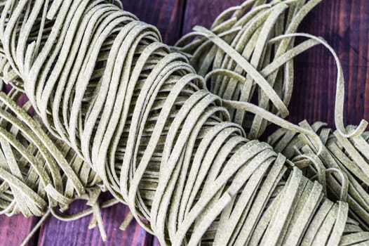 Raw spinach fettuccine pasta on wood tabel. Background