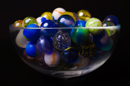 Colorful marbles in a bowl, isolated on black