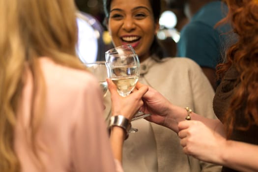 Three women toasting their glasses in a bar