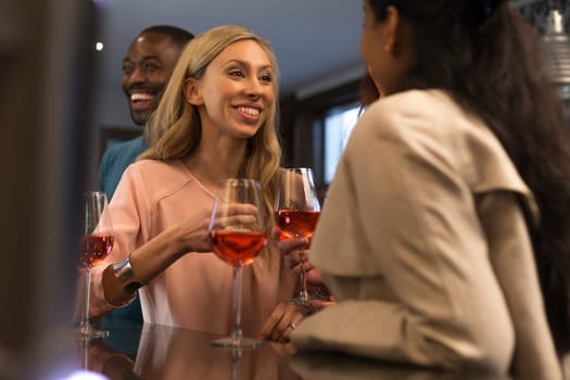 Two women can be seen enjoying a glass of red wine at a bar whilst chatting to each other.