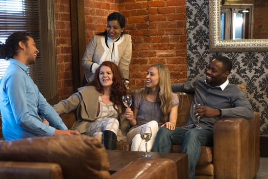 Small group of friends sitting in a bar, enjoying some drinks whilst chatting together.