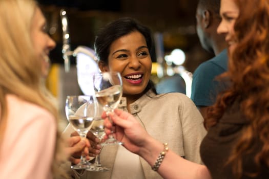 Three women toasting their glasses in a bar