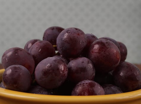 Bunch of red ripe grapes served in a orange bowl