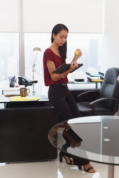 Office worker leaning on desk. The woman reads an email on tablet computer and holds an anti-stress yellow ball. She feels stressed and nervous