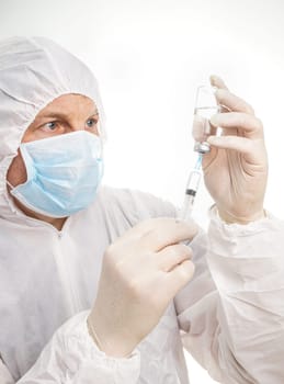 Man with syringe and vial in protective suit and mask