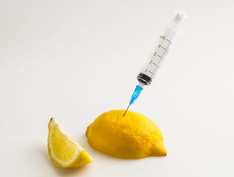 lemon with syringe, in slice and on white background