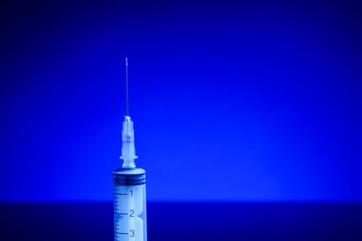 Syringe with needle, upright standing, isolated with background light